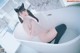 A woman sitting in a bathtub with a cat ears headband.