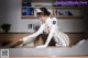 A woman in a white uniform is bending over a desk.