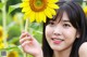 A woman holding a sunflower in front of her face.