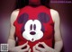 A woman wearing a red shirt with a mickey mouse face on it.