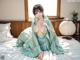 A woman in a green kimono sitting on a bed.