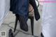 A woman in black stockings and high heels is sitting on a chair.