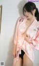 A woman in a pink robe is posing for a picture.