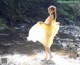 A woman in a yellow dress standing in a stream.