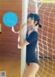 A woman in a polka dot bathing suit leaning against a pole.