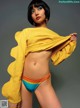 A woman in a yellow sweater and a colorful bikini.